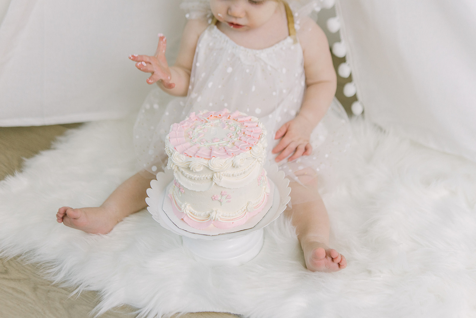 aby girl in gold polka dot dress with pink and white cake in tent setup – Meridian, Idaho.