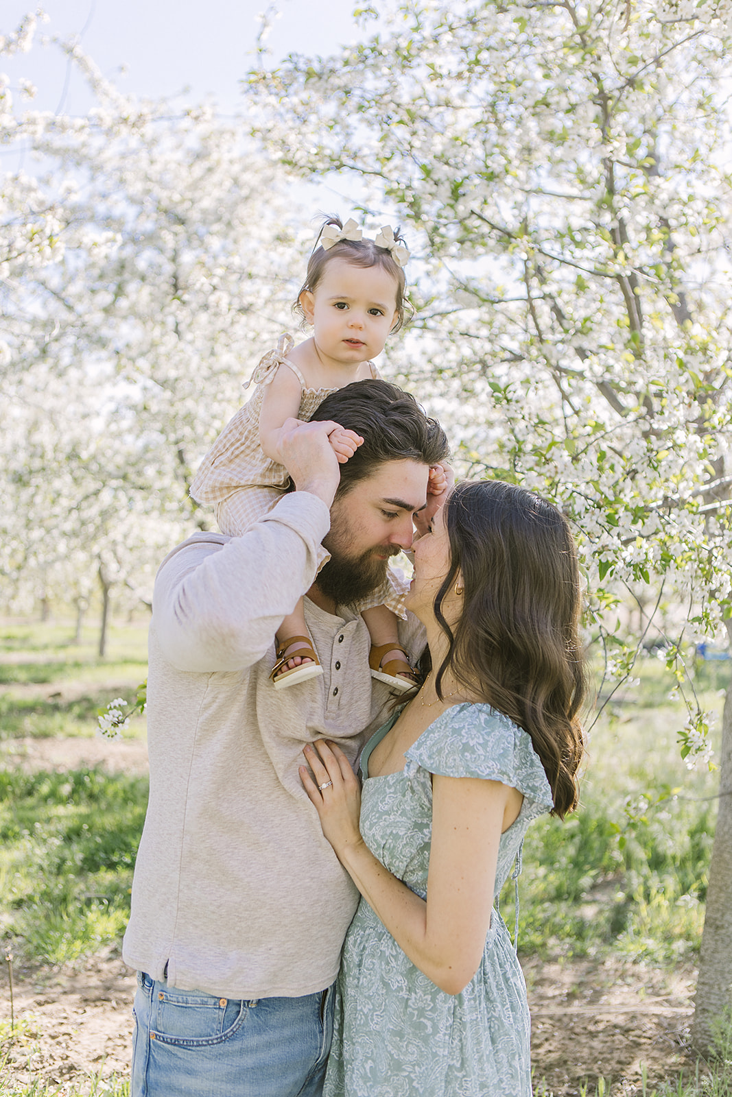 Family of three in blooming orchard at Cherry Hill Farms near Marsing, Idaho.